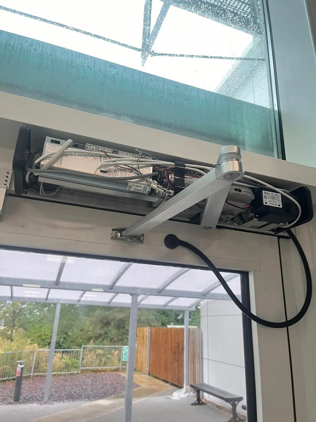 Automatic swing door operator and header above a glazed entrance