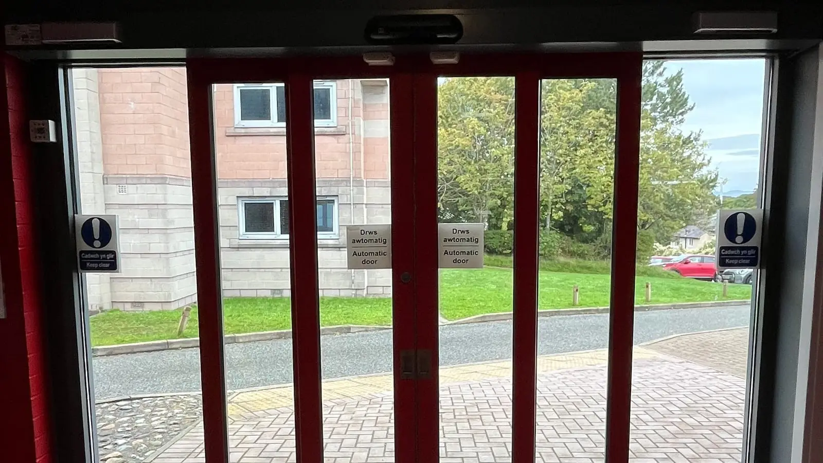 Red-framed automatic sliding double doors with bilingual automatic door signs