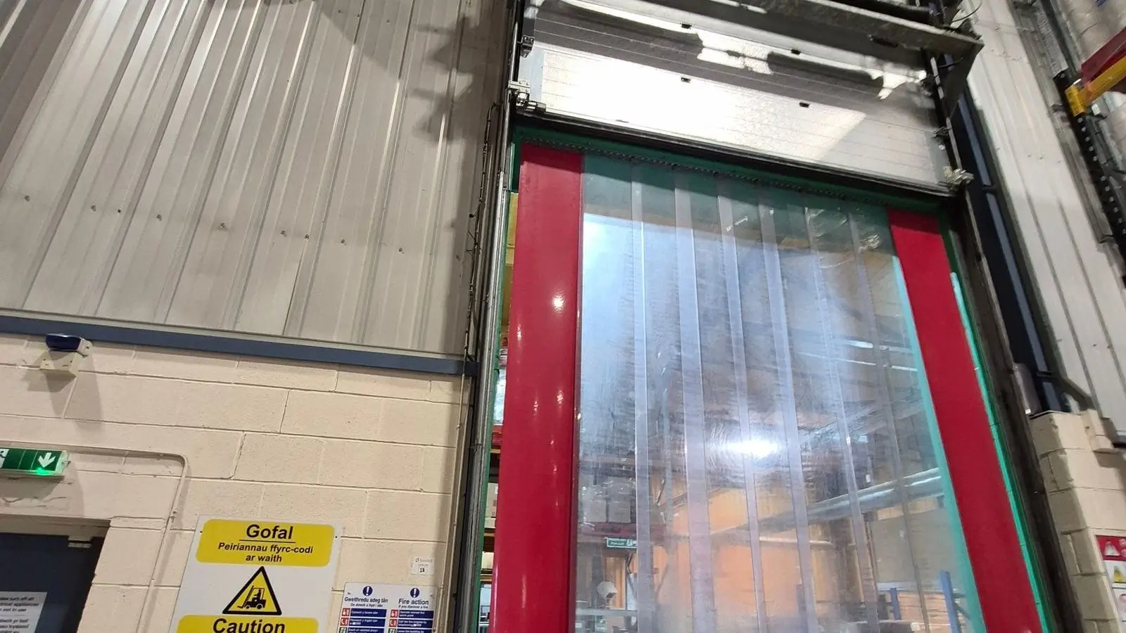 Engineer inspecting a high-speed industrial door beside its control cabinet