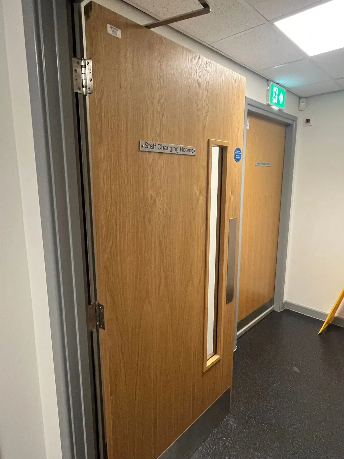 Oak fire door with a vision panel and door closer in a corridor